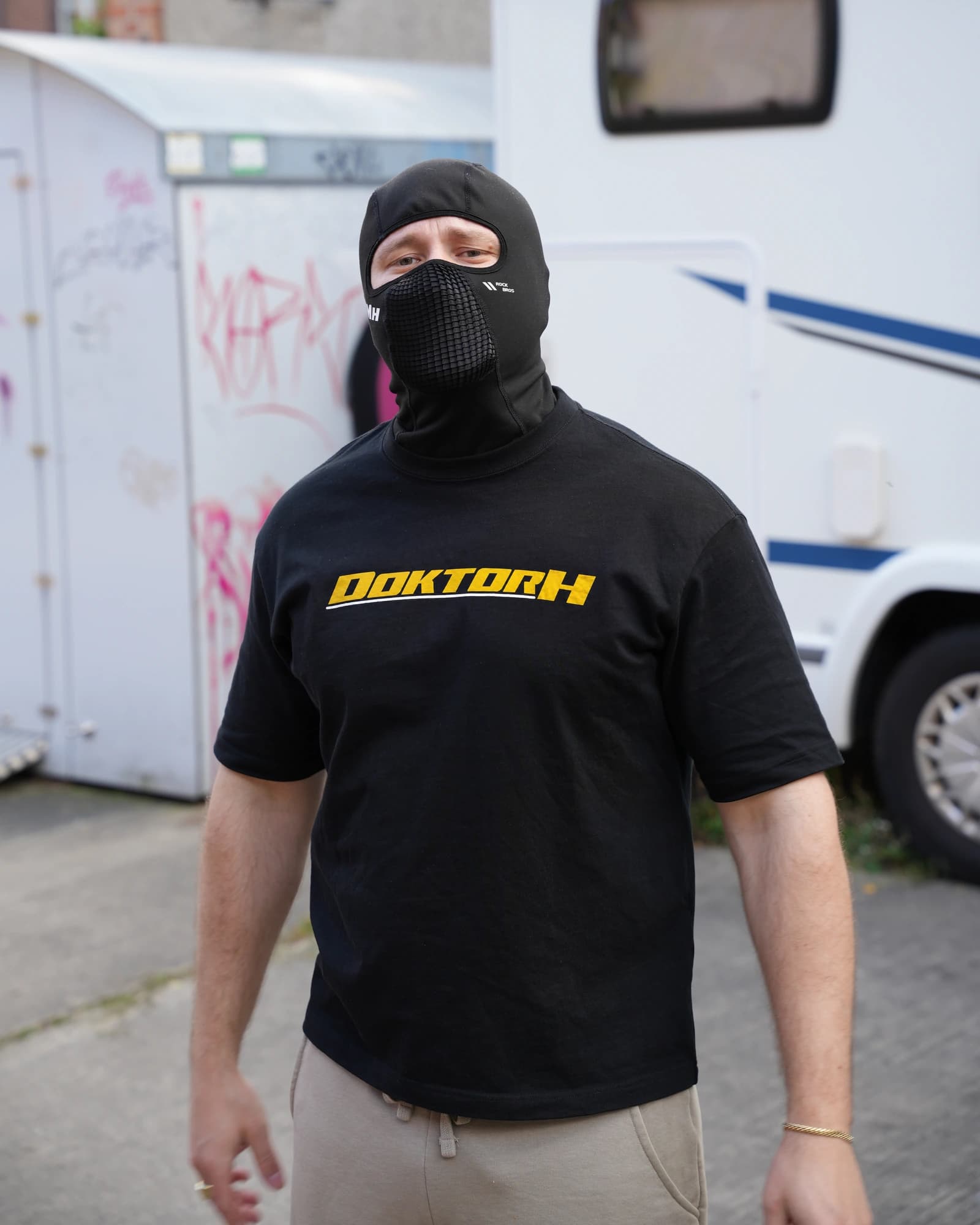Schwarzes DOKTOR-H-Shirt mit goldfarbenem Frontdruck, getragen